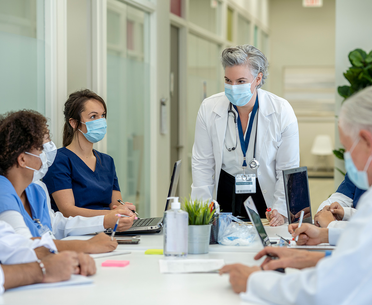 Doctors and nurses wearing masks at a meeting table