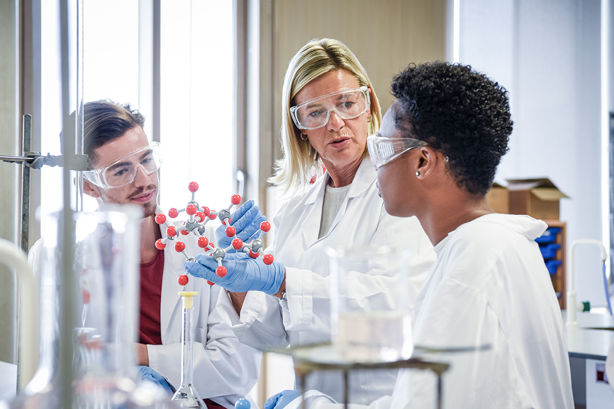 older female in lab coat explaining to students