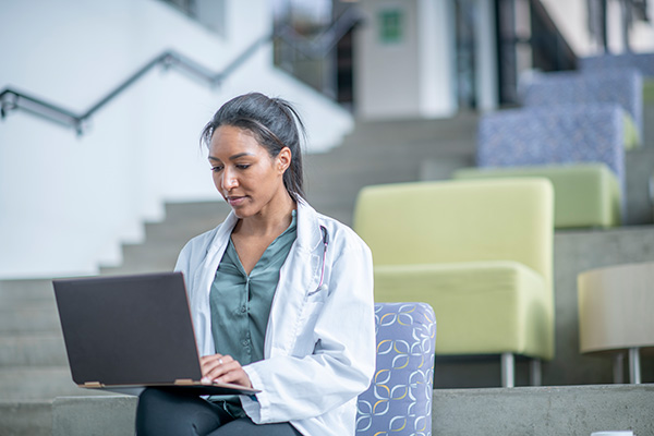 woman wearing lab coat on a laptop in college auditorium