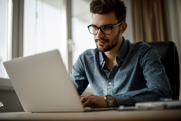 young man wearing glasses at laptop computer