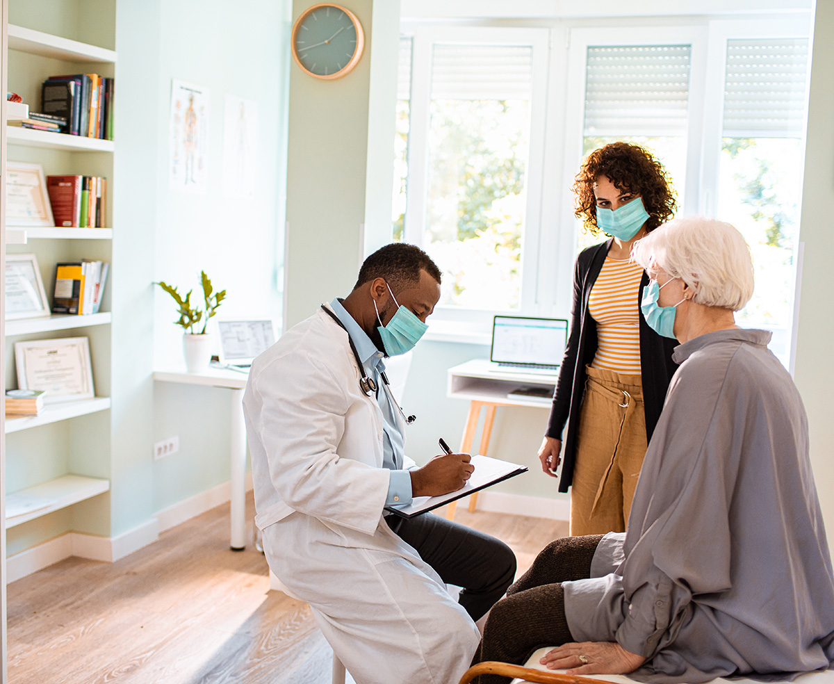 male doctor meeting elderly patient and adult daughter