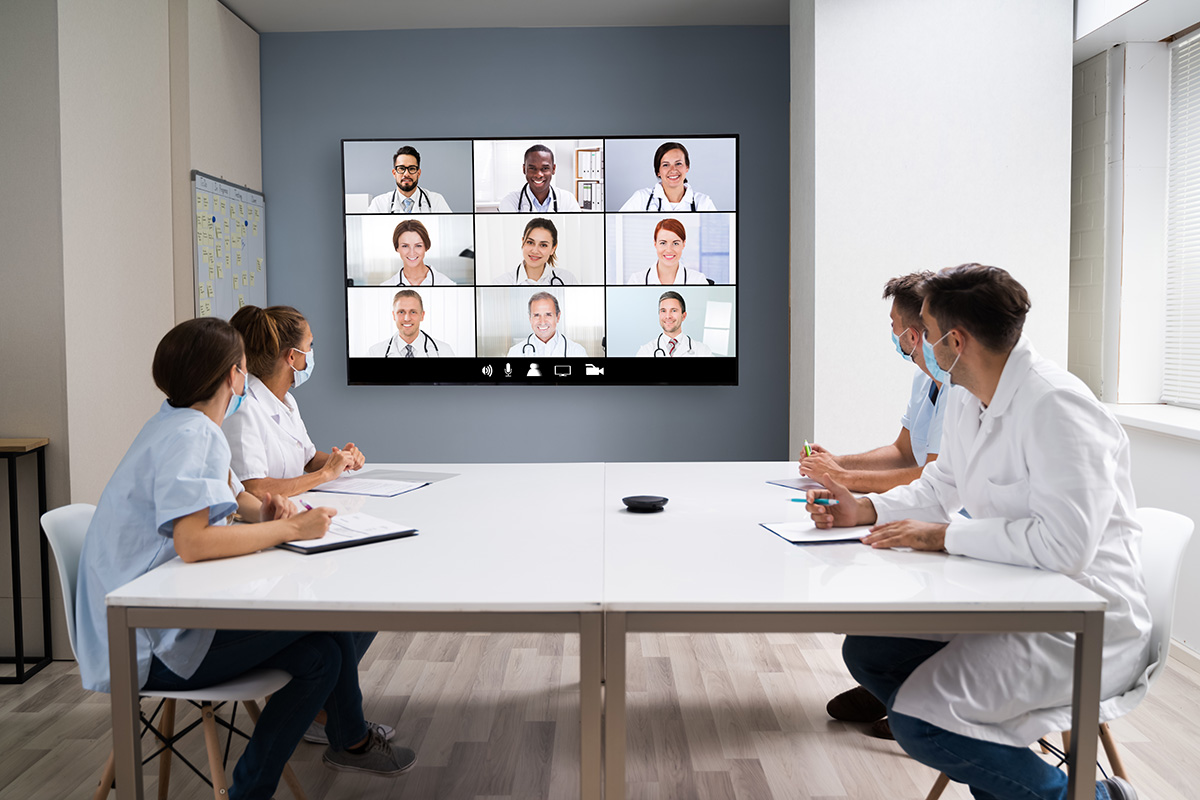 doctor at a table video calling doctors in a large screen