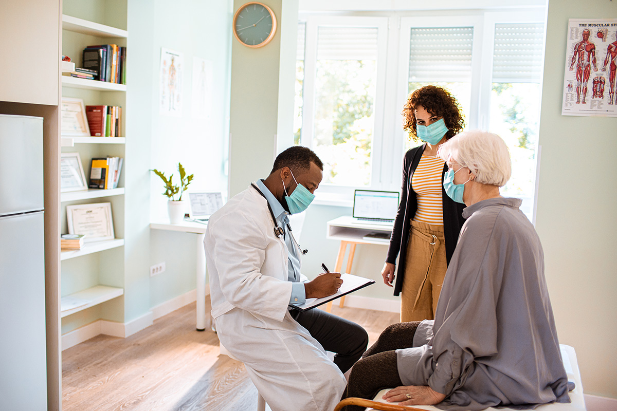 male doctor meeting elderly patient and adult daughter